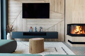 Una sala de estar moderna con un televisor de pantalla plana montado en una pared de madera, una chimenea empotrada y un mueble de entretenimiento minimalista.