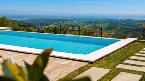 A rectangular swimming pool with a clear blue water surface, surrounded by a stone deck and a grassy area. - Vineyard Panorama Villa With Pool And Sauna (Jastrebarsko)
