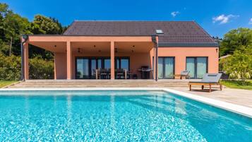 A modern house with a swimming pool, covered patio, and outdoor furniture.