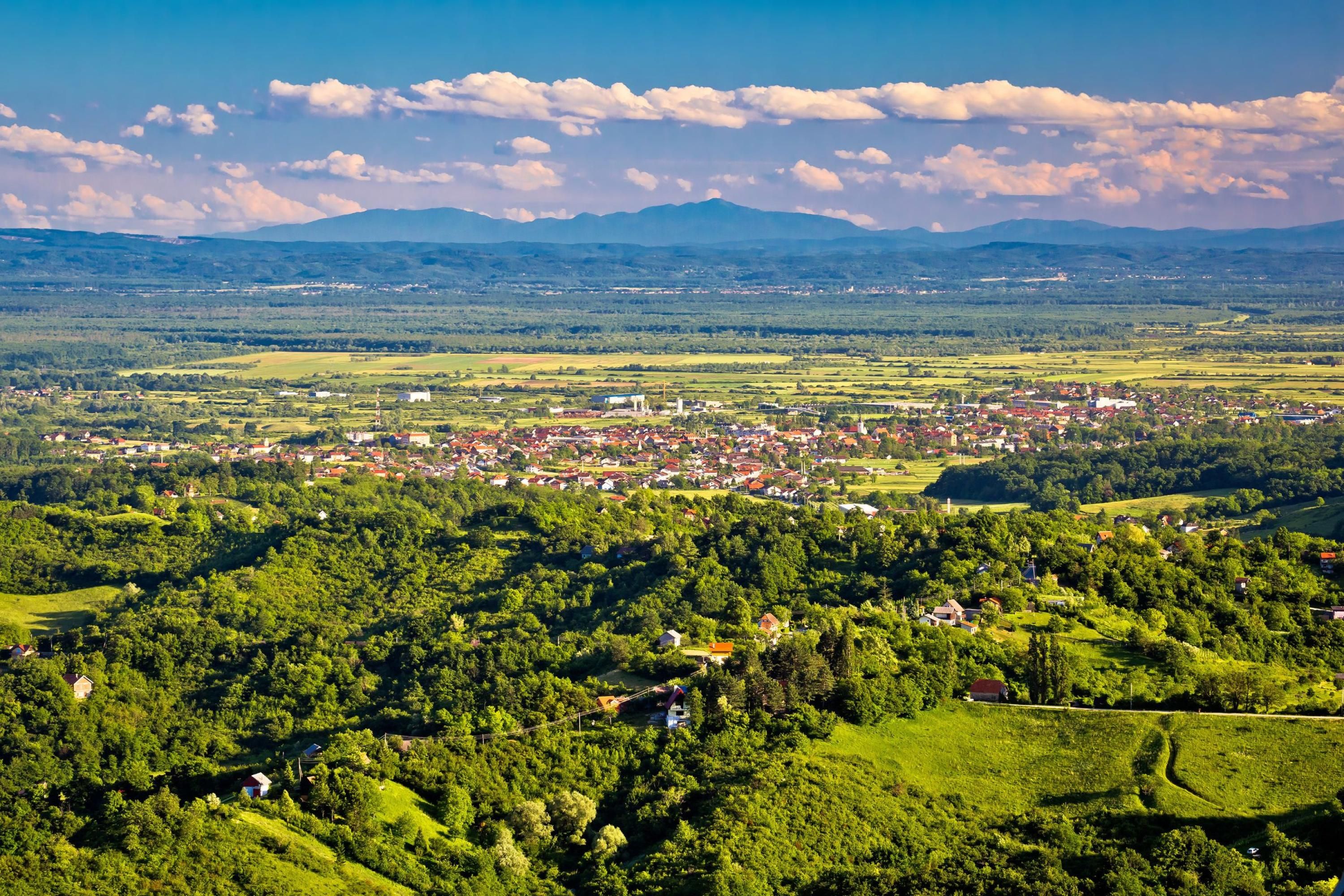 Een panoramisch uitzicht op een stadje gelegen in een vallei, omringd door heuvels en met een heldere lucht.
