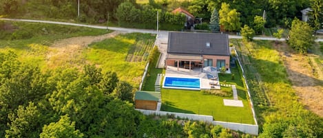 Una casa moderna con piscina, rodeada de exuberante follaje y un césped cuidado.