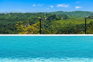 A swimming pool with a view of a green landscape and a fence.