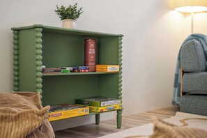 A green bookshelf with various board games and a lamp. - Palm Cove—Tranquil Coastal Retreat with Fire Pit (Dunsborough)