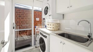 Cocina compacta con lavadora, un lavabo y un pequeño espacio de almacenamiento.