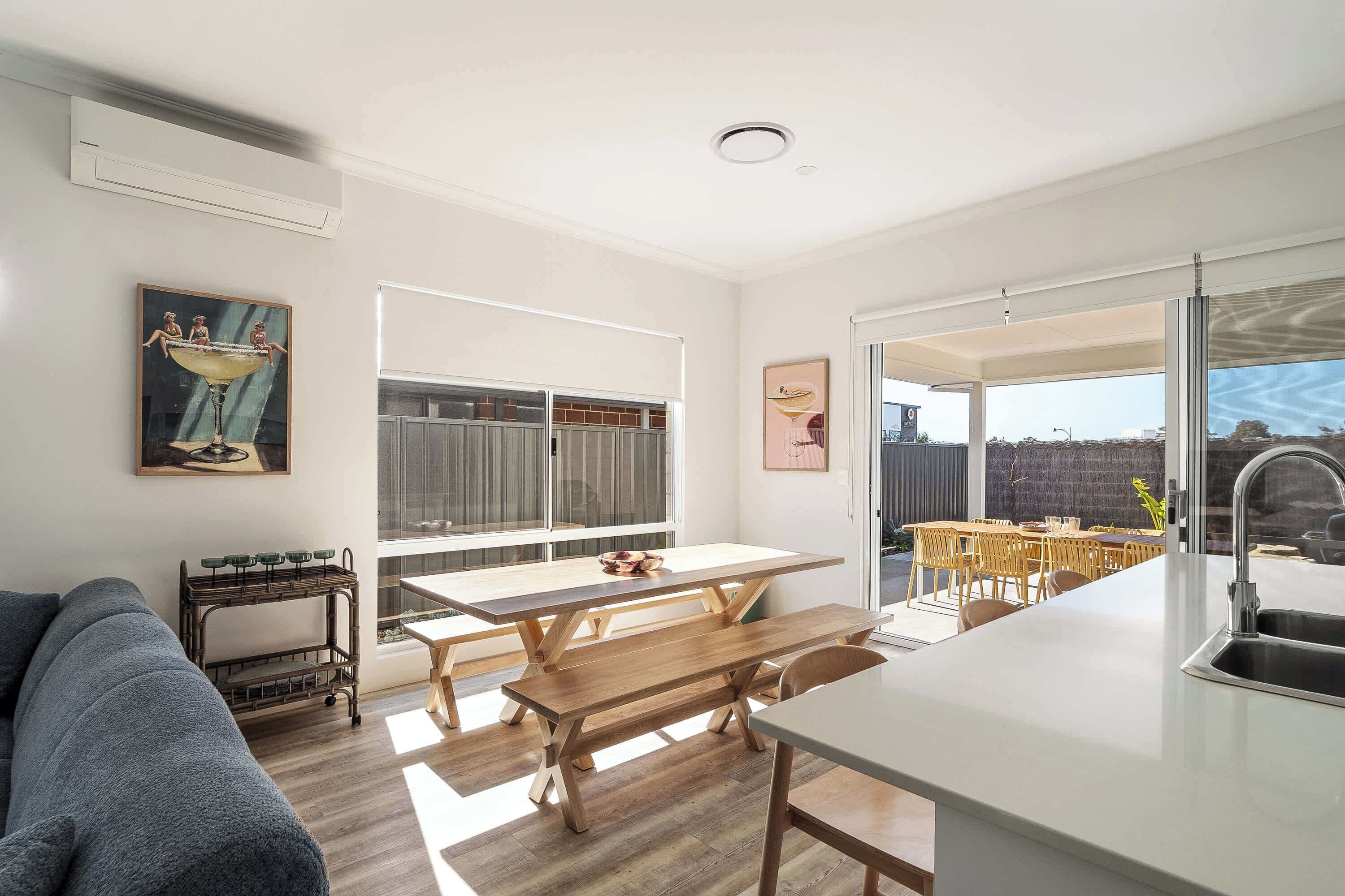A modern kitchen with a dining area, wooden furniture, and artwork on the walls.