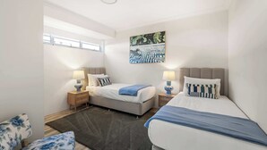 Una habitación de hotel moderna con una cama, mesitas de noche, una ventana y un cuadro en la pared.