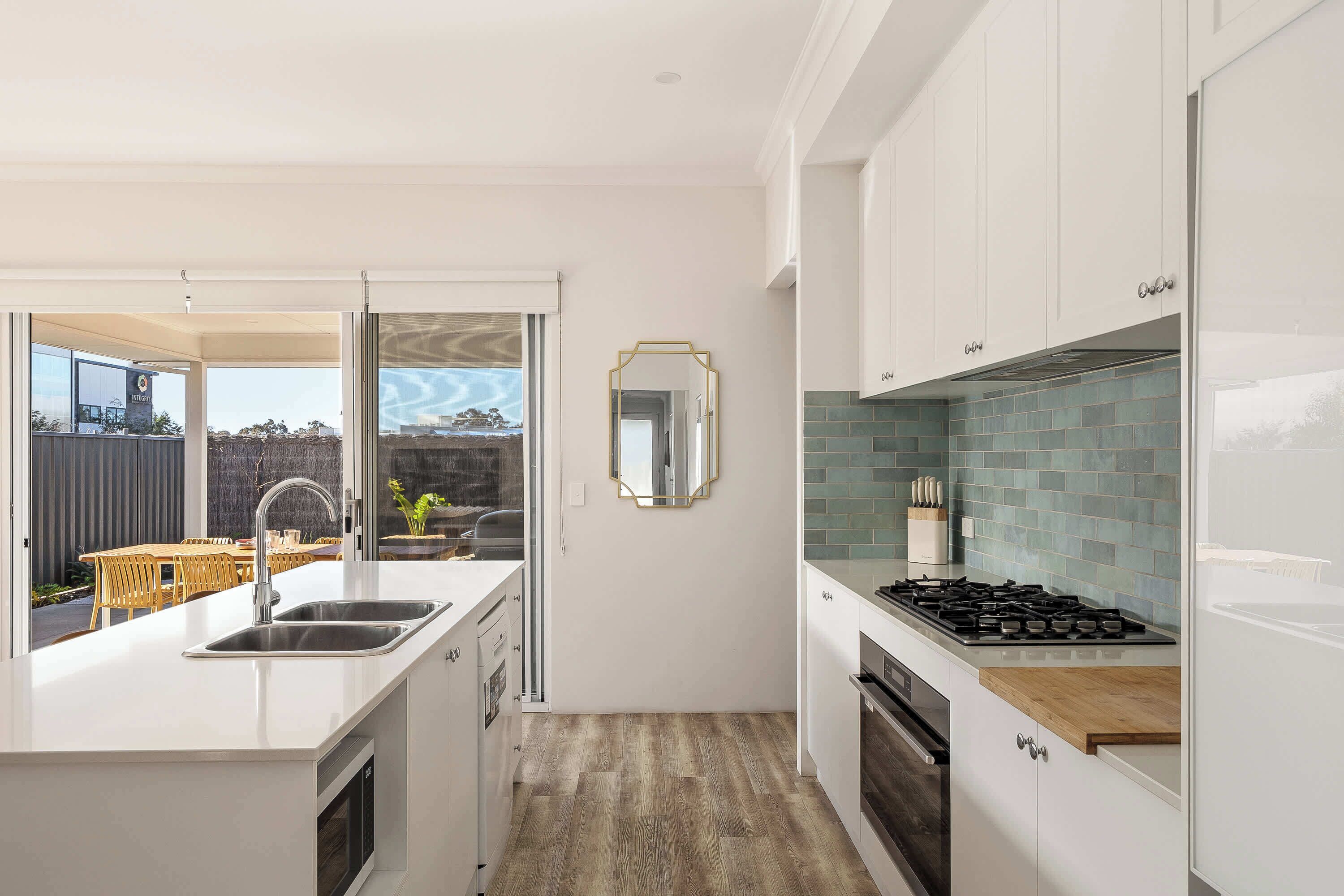 A modern kitchen with a built-in stove, a sink, and a dining area with a view.
