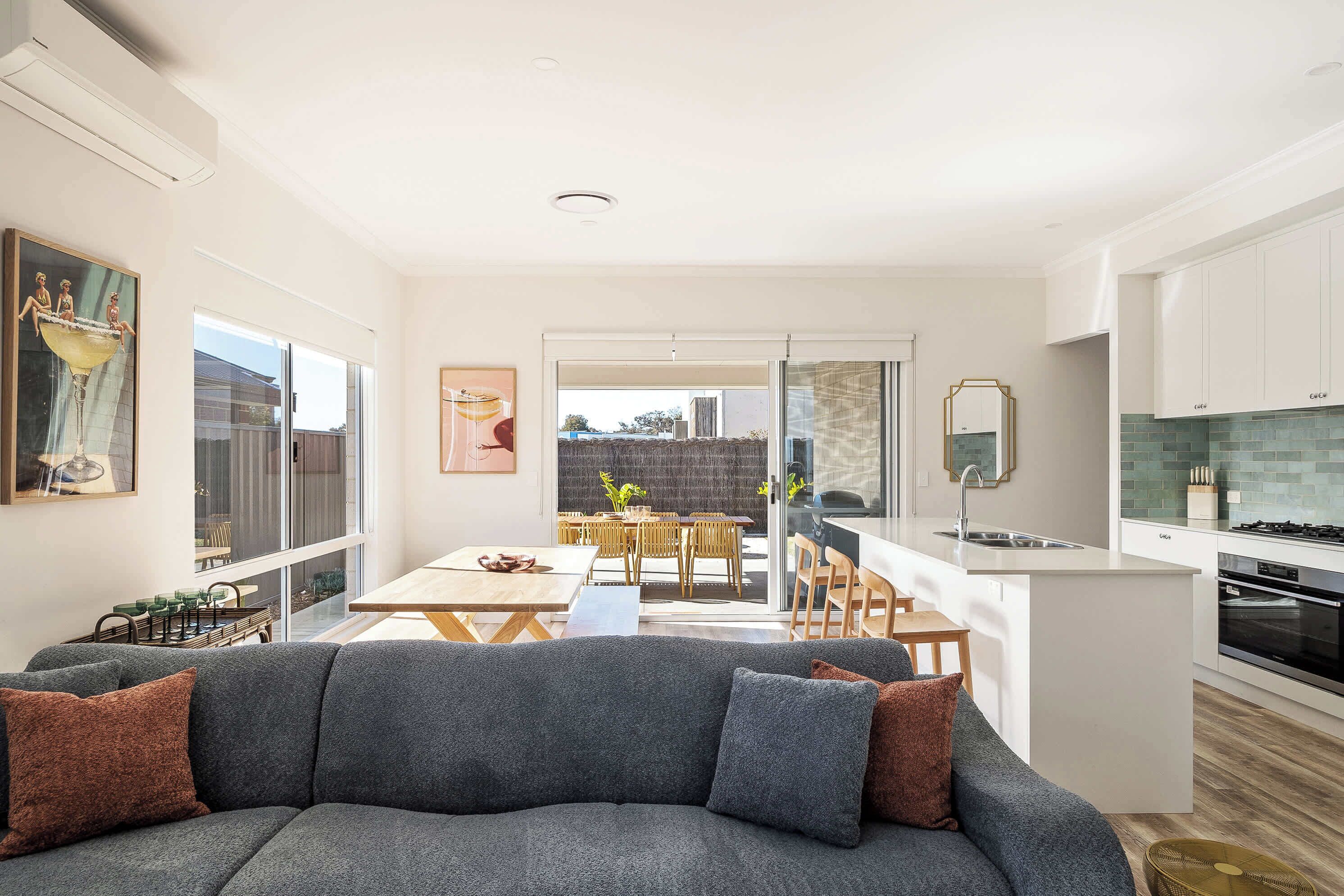 A modern kitchen with white cabinetry, a built-in oven, and a stainless steel sink.
