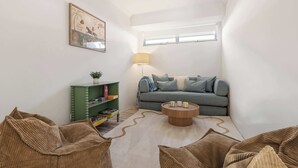 Un espacio habitable compacto con sofá, mesa de centro, estantería y lámpara.