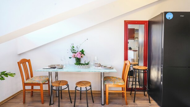 A dining area with a table, chairs, and a refrigerator. - Ema Studio on the Main Promenade (Koper)