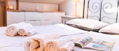 A neatly made bed with rolled towels and an open magazine.