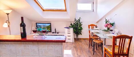 A kitchen with a dining area, a TV, a wine bottle, and a plant.