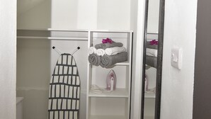 A bathroom with a towel rack, a mirror, and a shelf with towels and an iron. - Cozy studio apartment in beautiful Monchy with AC and king bed for your comfort. (Monchy)