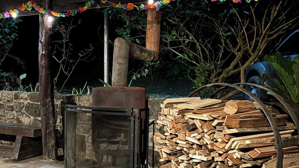 An outdoor wood stove with a pile of firewood and a bench nearby. - Family & Pet friendly•Nestled in the forest•Trails•Waterfalls 13 km away•8 beds• (Luisa)