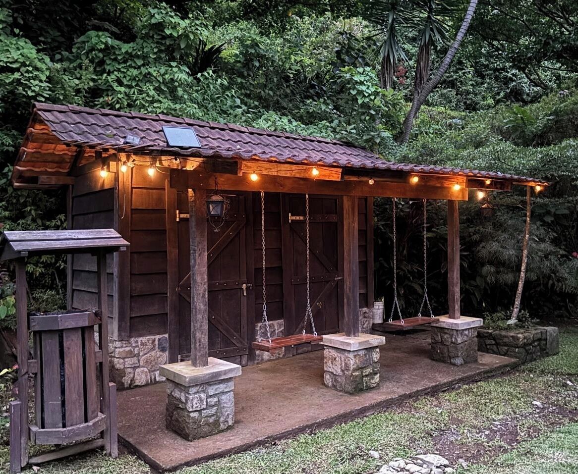 A rustic wooden cabin with a porch, stone steps, and hanging lights.