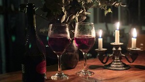 A dimly lit table with a bottle, two glasses of red liquid, and a candle holder with lit candles. - Family & Pet friendly•Nestled in the forest•Trails•Waterfalls 13 km away•8 beds• (Luisa)