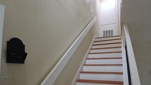 A staircase with white walls and wooden steps leading to a landing. - Charming 3-bedroom house in peaceful San Antonio near military bases (San Antonio)
