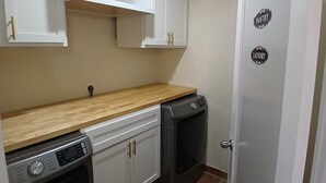 A compact kitchen with white cabinets, a wooden countertop, a dishwasher, and a washing machine. - Charming 3-bedroom house in peaceful San Antonio near military bases (San Antonio)
