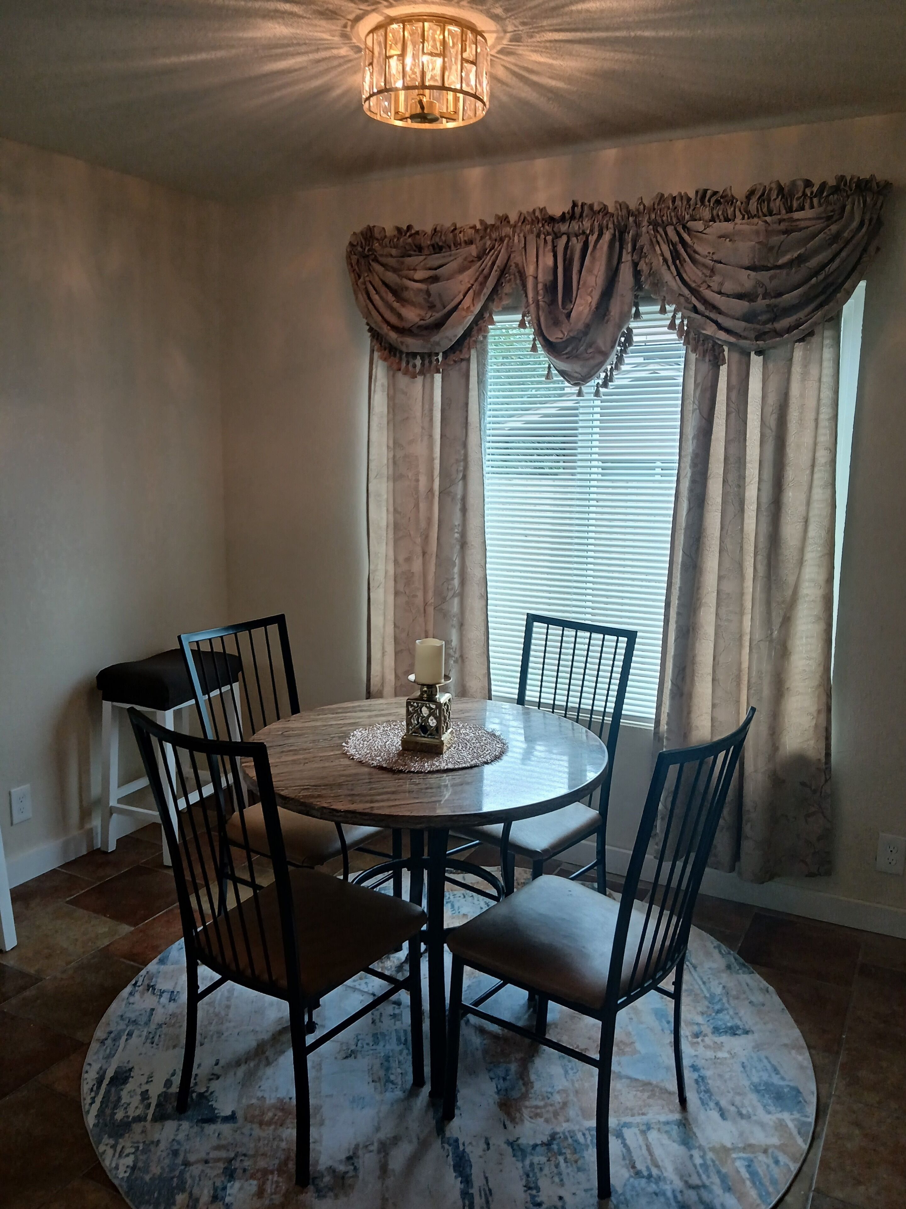 Un coin repas avec une table ronde, six chaises, un centre de table décoré d’une bougie et un lustre.