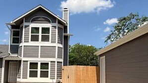 A two-story house with a garage, a wooden fence, and a clear sky. - Charming 3-bedroom house in peaceful San Antonio near military bases (San Antonio)