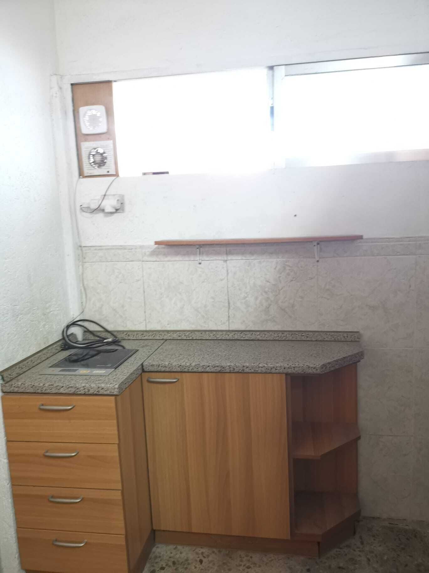 Una pequeña cocina con armarios de madera, una encimera y una ventana sobre el lavabo.