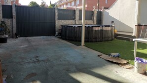 Un espacio exterior techado con piso de concreto, piscina de madera y pared de piedra.