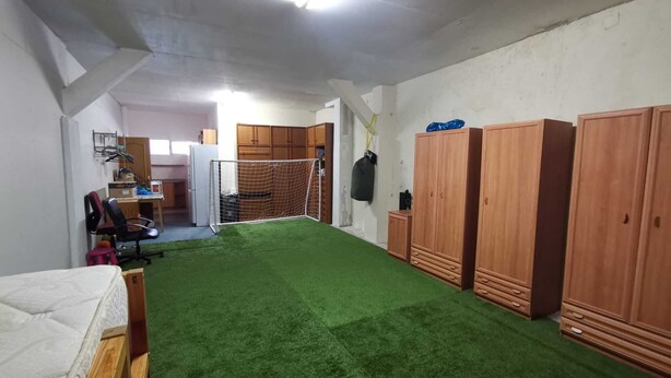 Una habitación con piso de césped artificial verde, armarios de madera, un escritorio con una silla y una cama.