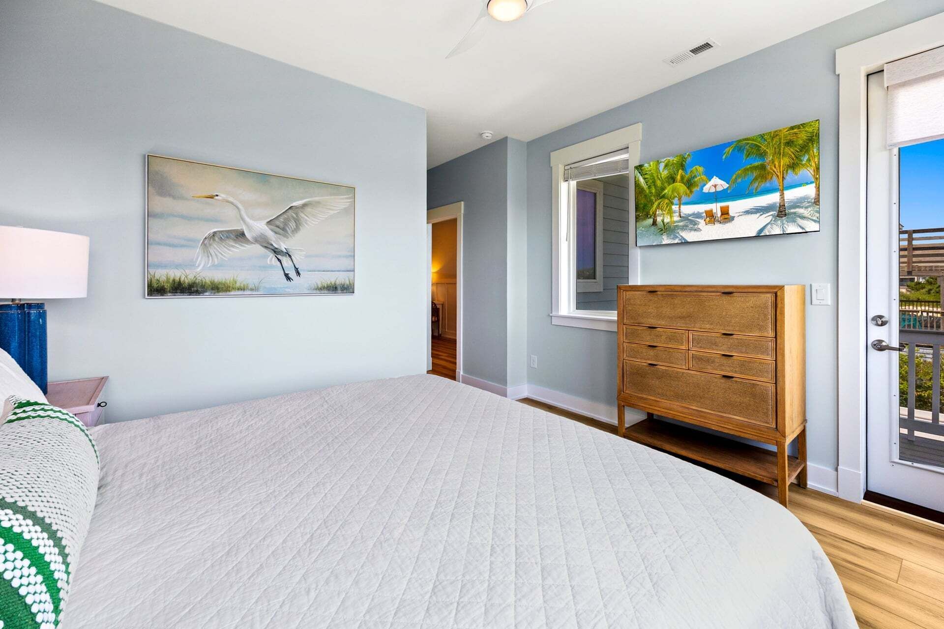 Une chambre à coucher avec un grand lit, une commode en bois et un tableau représentant un oiseau.