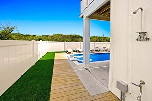 A backyard with a pool, wooden deck, and white fence. - Coastal Bliss - Oceanfront w/ views, pool, hot tub, and easy beach access. (Corolla)