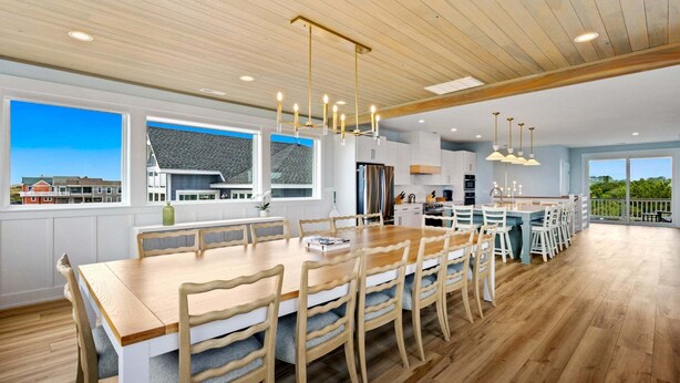 Een ruime keuken met een groot kookeiland, houten vloeren en hanglampen.