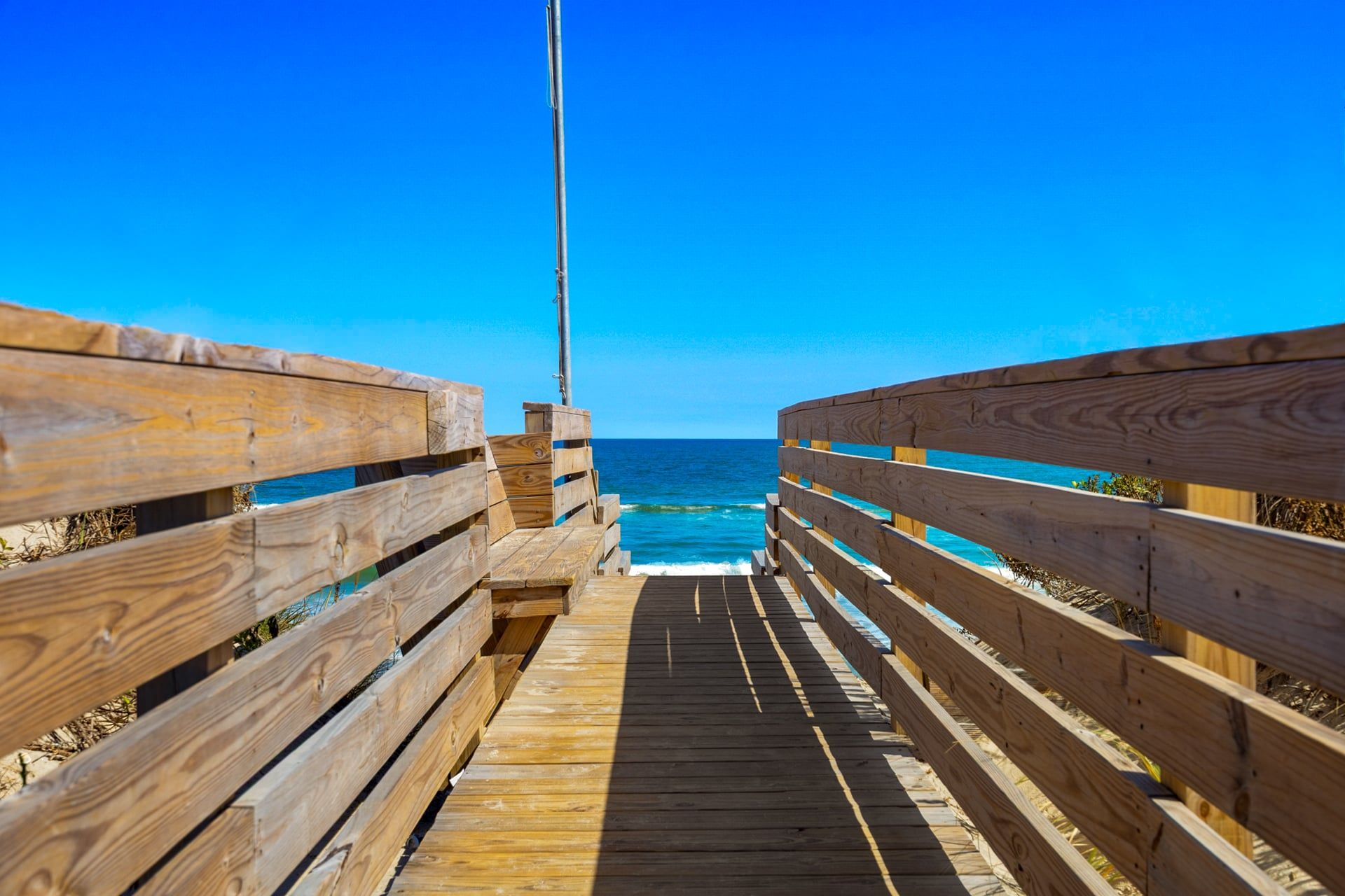 Un muelle de madera que conduce a una playa con agua azul cristalina.