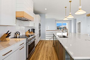 Eine moderne Küche mit weißen Schränken, Edelstahlgeräten und Holzboden.