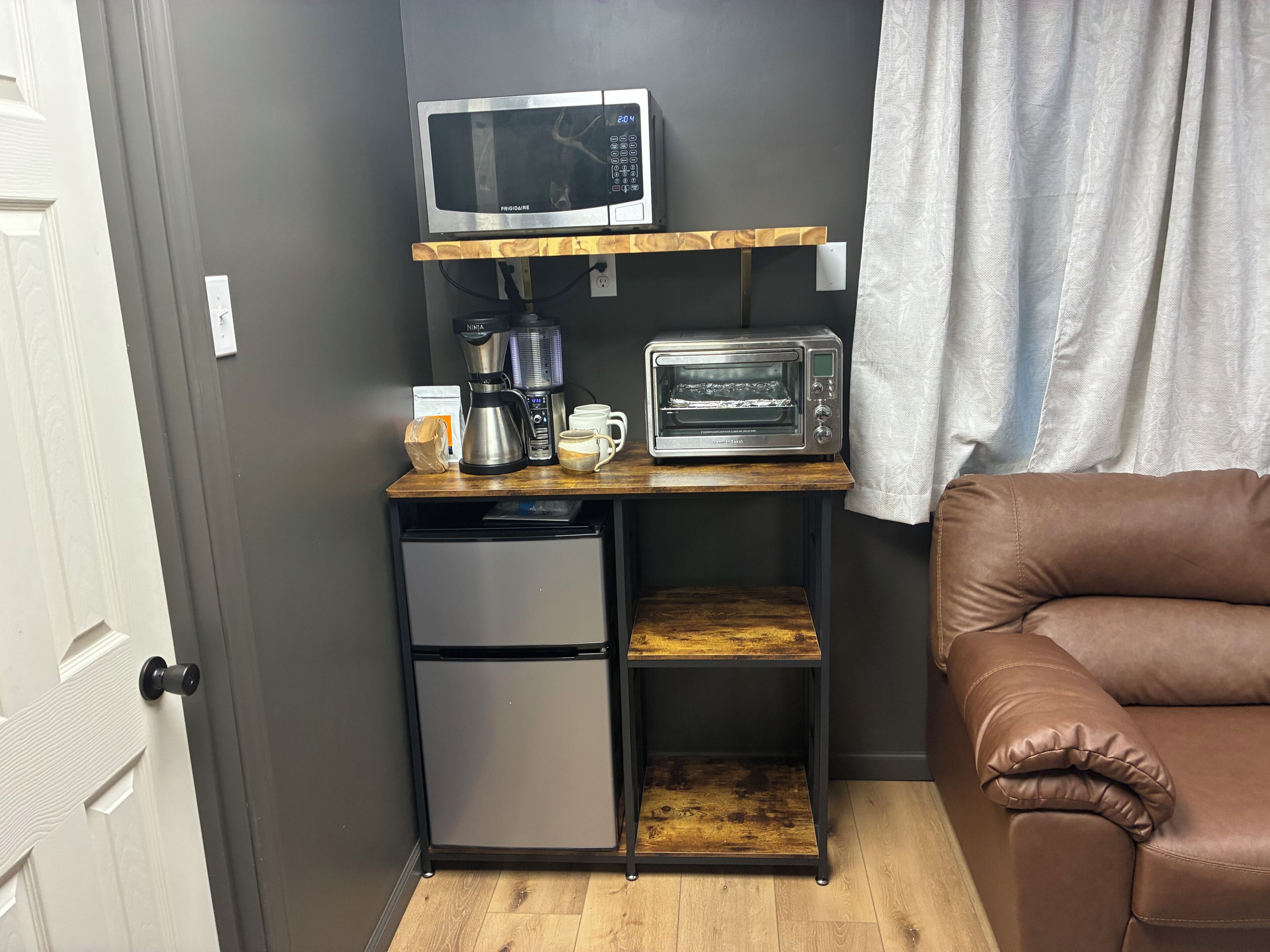 A compact kitchenette with a microwave, coffee maker, toaster, and mini-fridge.