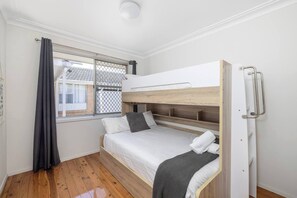 Habitación con literas, ventana, cortina y puerta con manija.