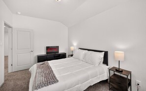 A hotel room with a bed, bedside tables, a television, and a door. - Modern Comfort, Prime Location/SeaWorld/Six Flags (San Antonio)