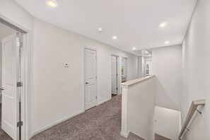 A hallway with white walls, carpeted floors, and recessed ceiling lights. - Modern Comfort, Prime Location/SeaWorld/Six Flags (San Antonio)