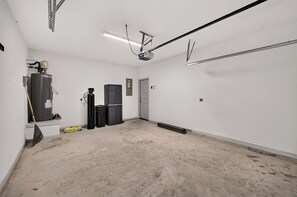 A clean, empty room with a water heater, a trash bin, and a door. - Modern Comfort, Prime Location/SeaWorld/Six Flags (San Antonio)
