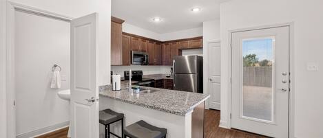 A modern kitchen with granite countertops, stainless steel appliances, and wooden cabinets.