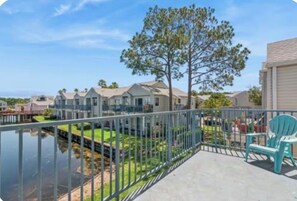 A residential area with houses, a tree, a body of water, and a balcony with a chair. - Cozy 2-bedroom condo with AC in delightful Orlando (Orlando)
