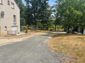 Zona residencial amb una calçada pavimentada, una casa amb un balcó i un pati tancat amb arbres.