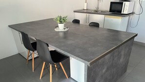 A modern kitchen with a grey countertop, two black chairs, a potted plant, and a microwave. - 3-room NE apartment on the garden level (Varetz)