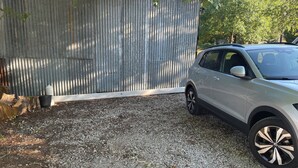 A gravel driveway leading to a vehicle parked beside a corrugated metal fence. - 3-room NE apartment on the garden level (Varetz)
