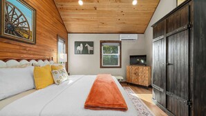 Ein Schlafzimmer mit einem großen Bett, Holzbalkendecke und einem Kleiderschrank.