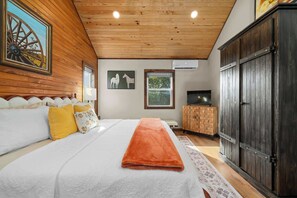 A bedroom with a large bed, wooden ceiling, and a wardrobe. - Luckenbach House, Hot tub, Views! (Fredericksburg)