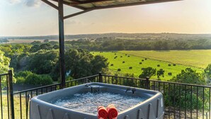 Ein Whirlpool auf einem Balkon mit Blick auf ein grünes Feld und Bäume.