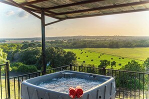 A hot tub on a balcony with a view of a green field and trees. - Luckenbach House, Hot tub, Views! (Fredericksburg)
