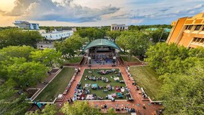 An outdoor amphitheater with a stage, surrounded by green lawns and trees. - Mins 2: VA, UF SanteFe U, UF Shands, HCA ,Airport (Gainesville)