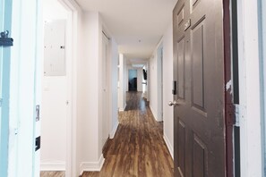 A hallway with wooden flooring, white walls, and doors on both sides.