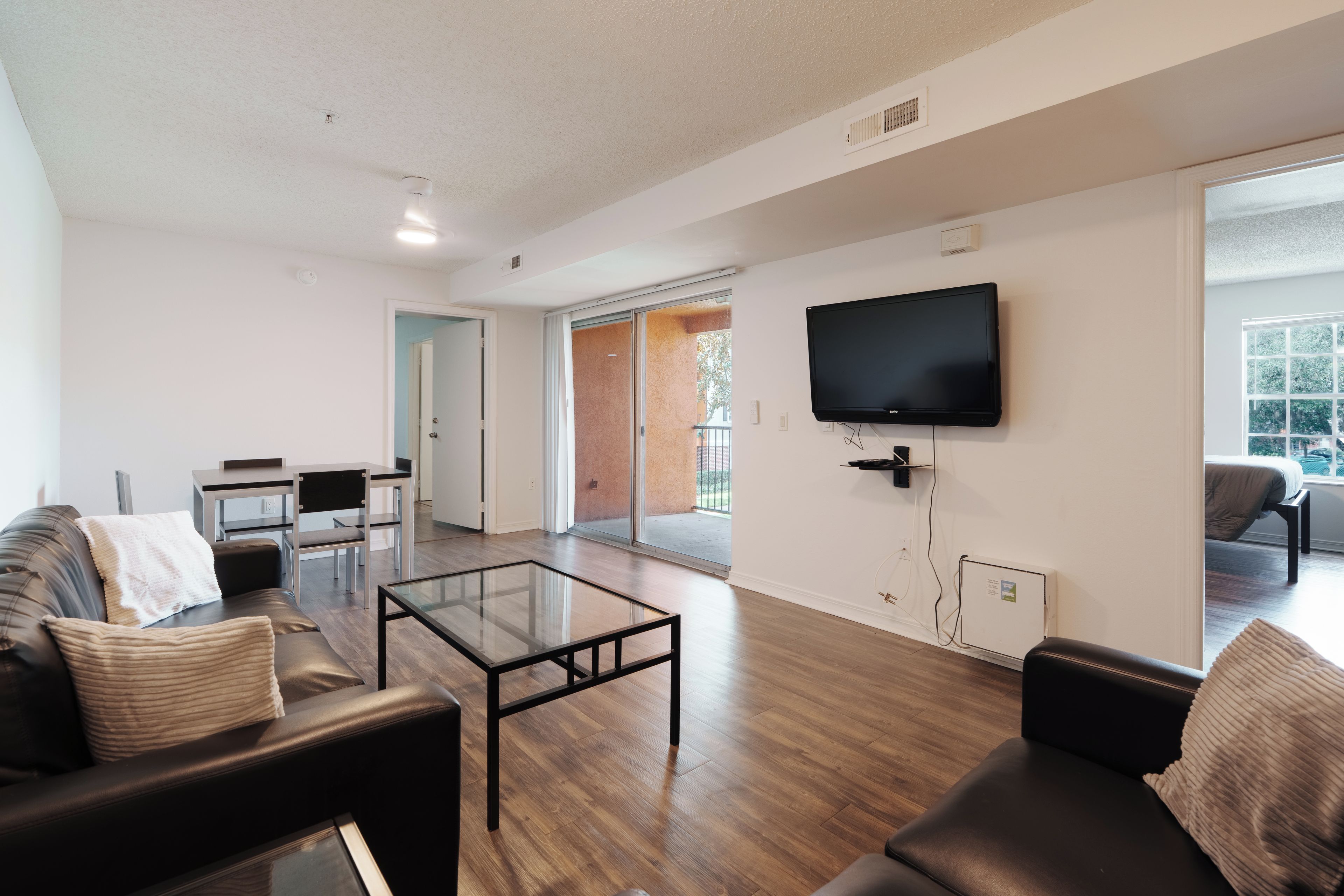 Una sala moderna con un sofá, una mesa de centro y un televisor de pantalla plana montado en la pared.