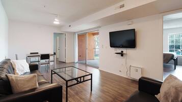 Una sala moderna con un sofá, una mesa de centro y un televisor de pantalla plana montado en la pared.